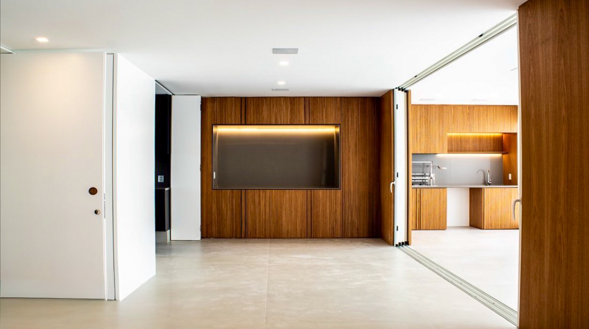 Sala integrada com painel de madeira e portas de correr