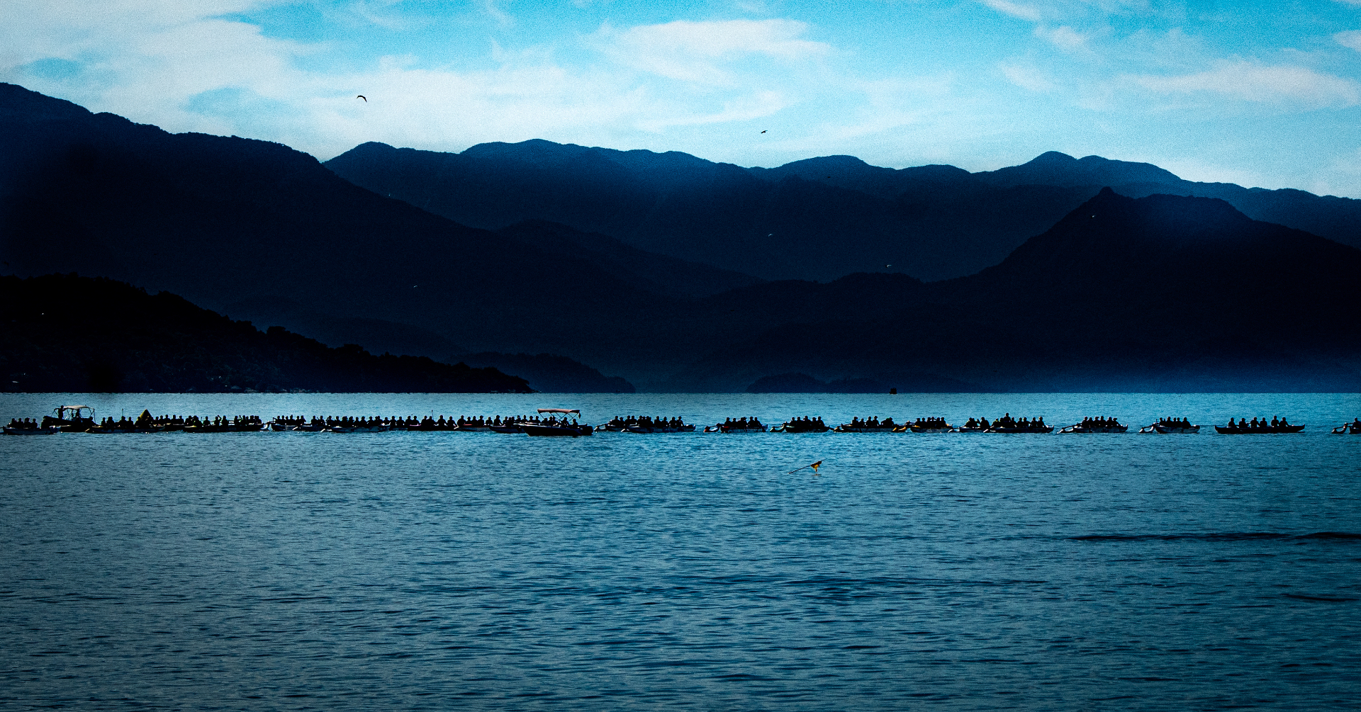 Canoas havaianas em silhueta ao amanhecer com montanhas ao fundo