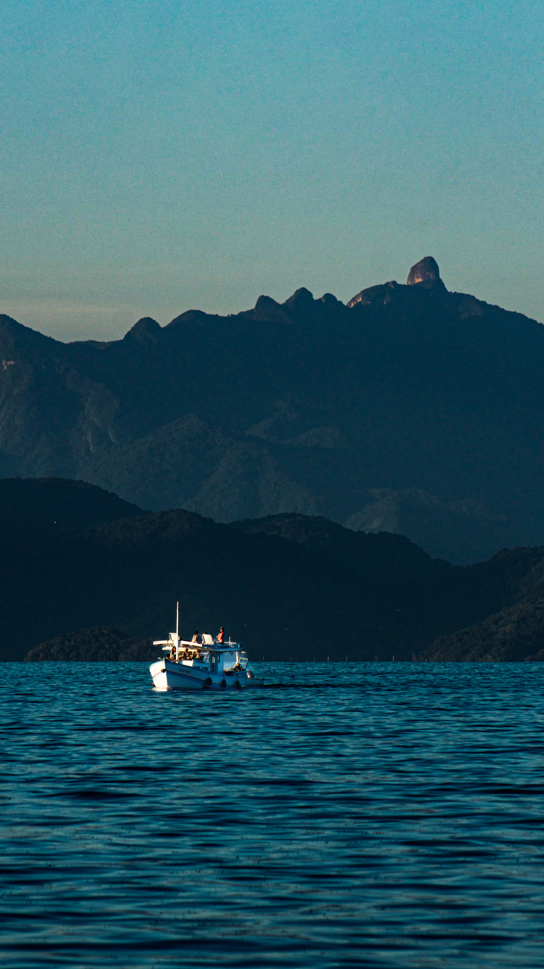 Barco de pesca azul com montanha ao fundo