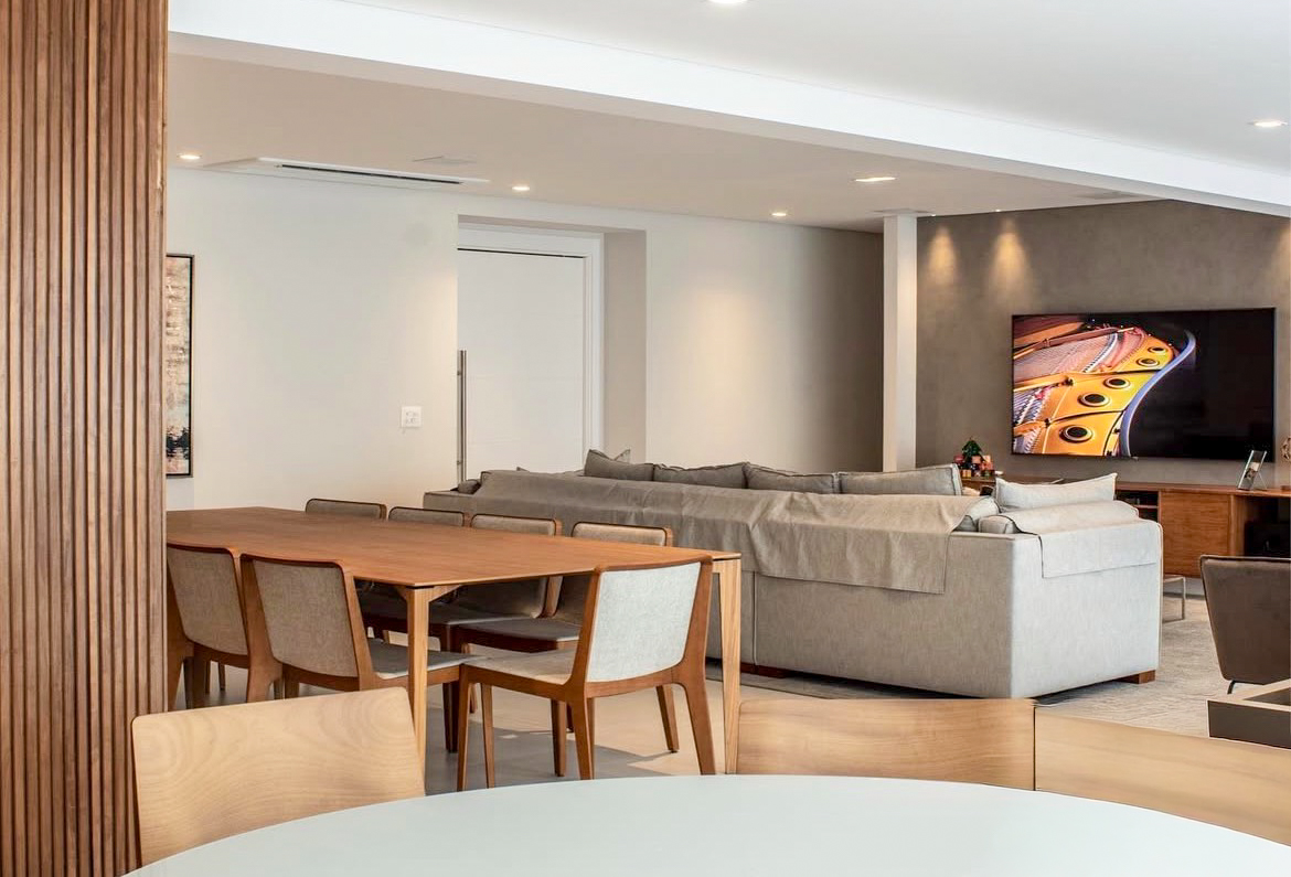 Sala de jantar e estar com mesa de madeira e sofá cinza